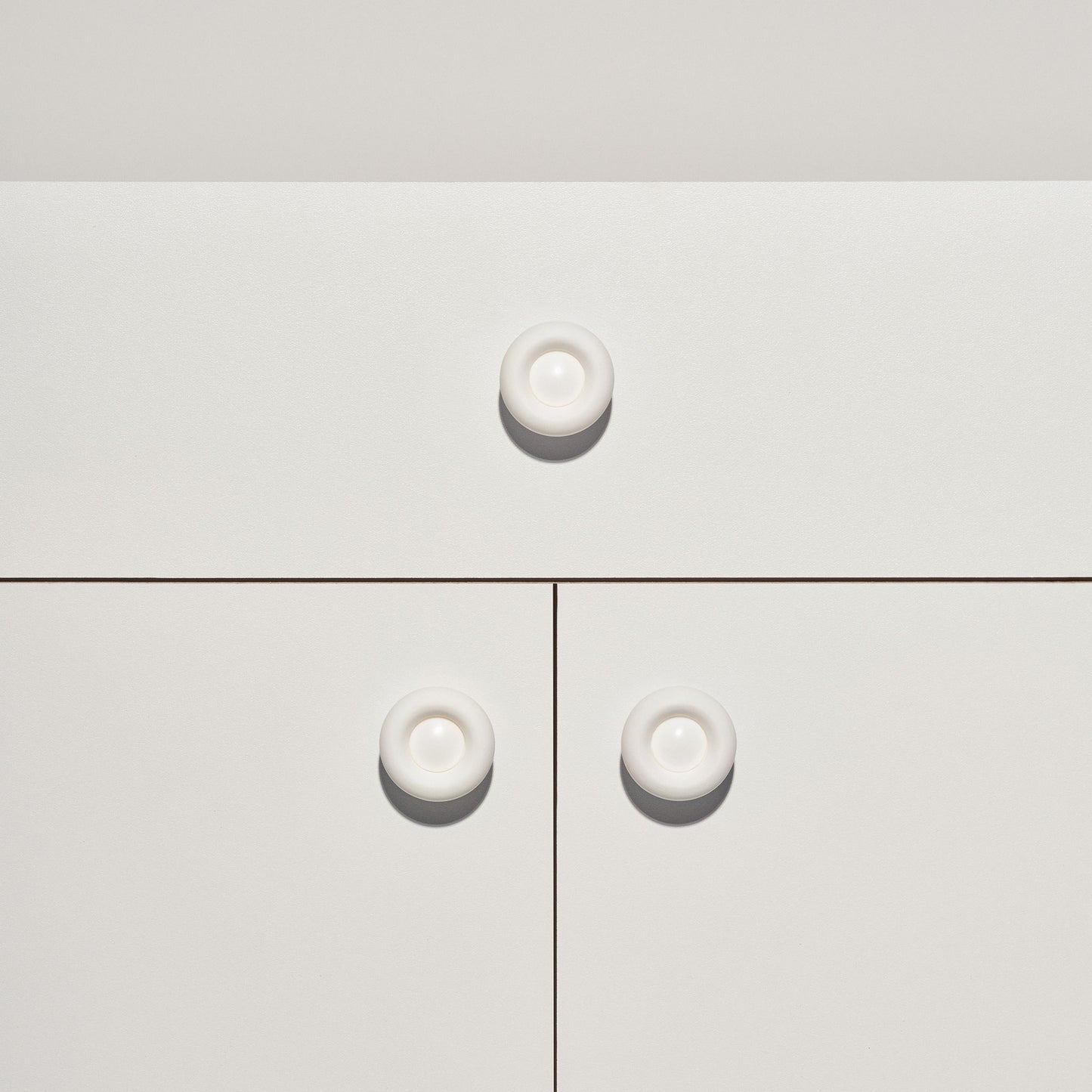 White cabinet with signal white colored cabinet knobs on a white background