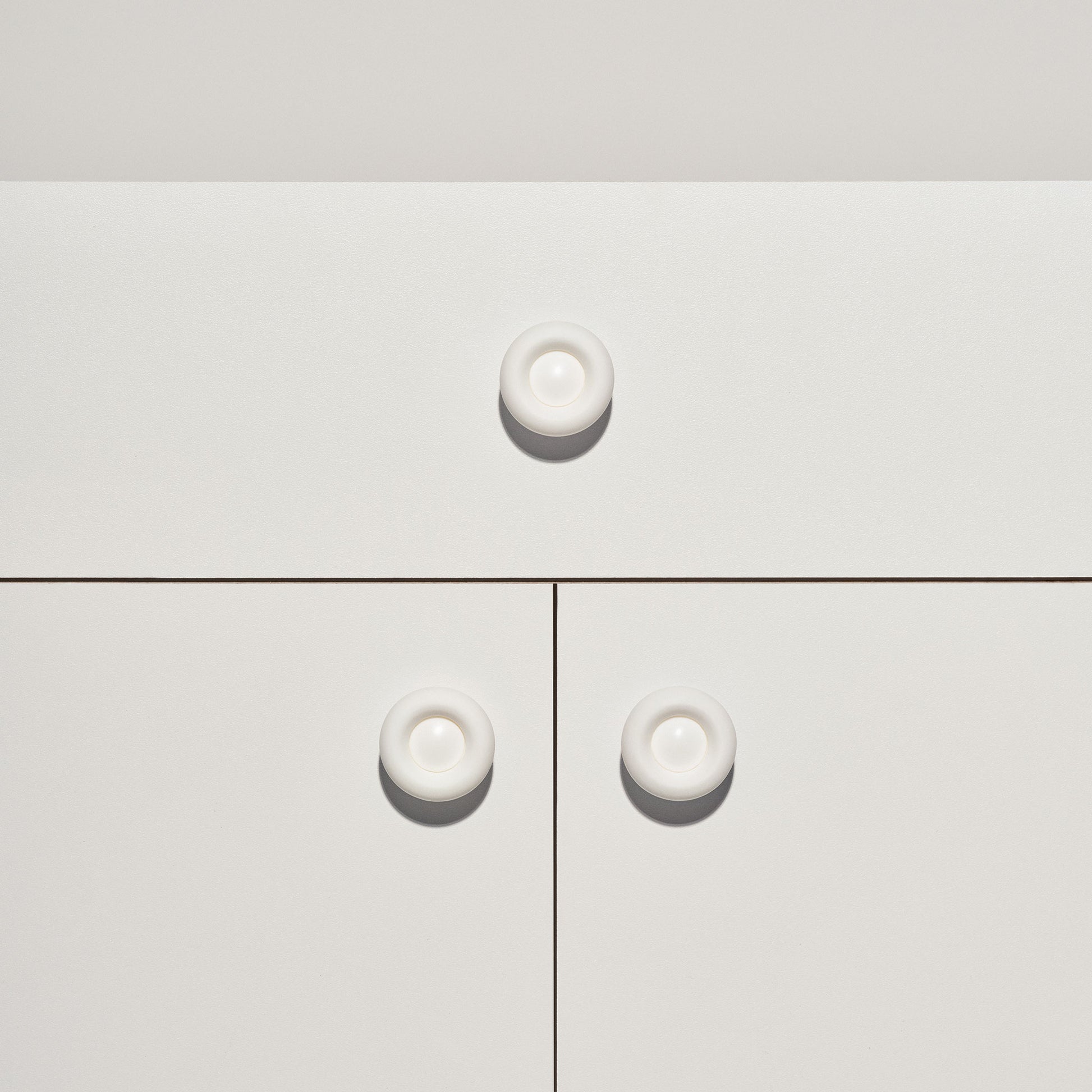 White cabinet with signal white colored cabinet knobs on a white background