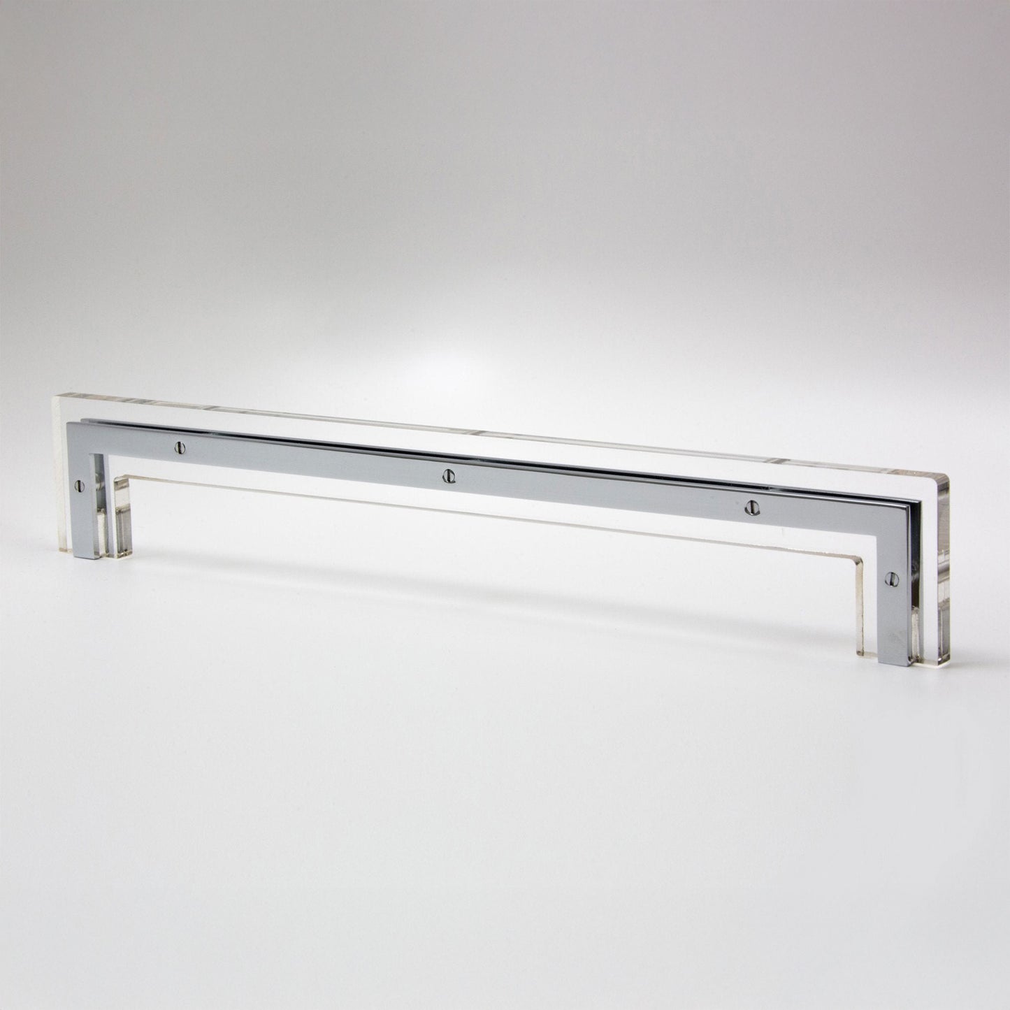 A long, slim rectangular cabinet handle polished silver/chrome finish and small screw details, photographed on a clean light gray studio background.