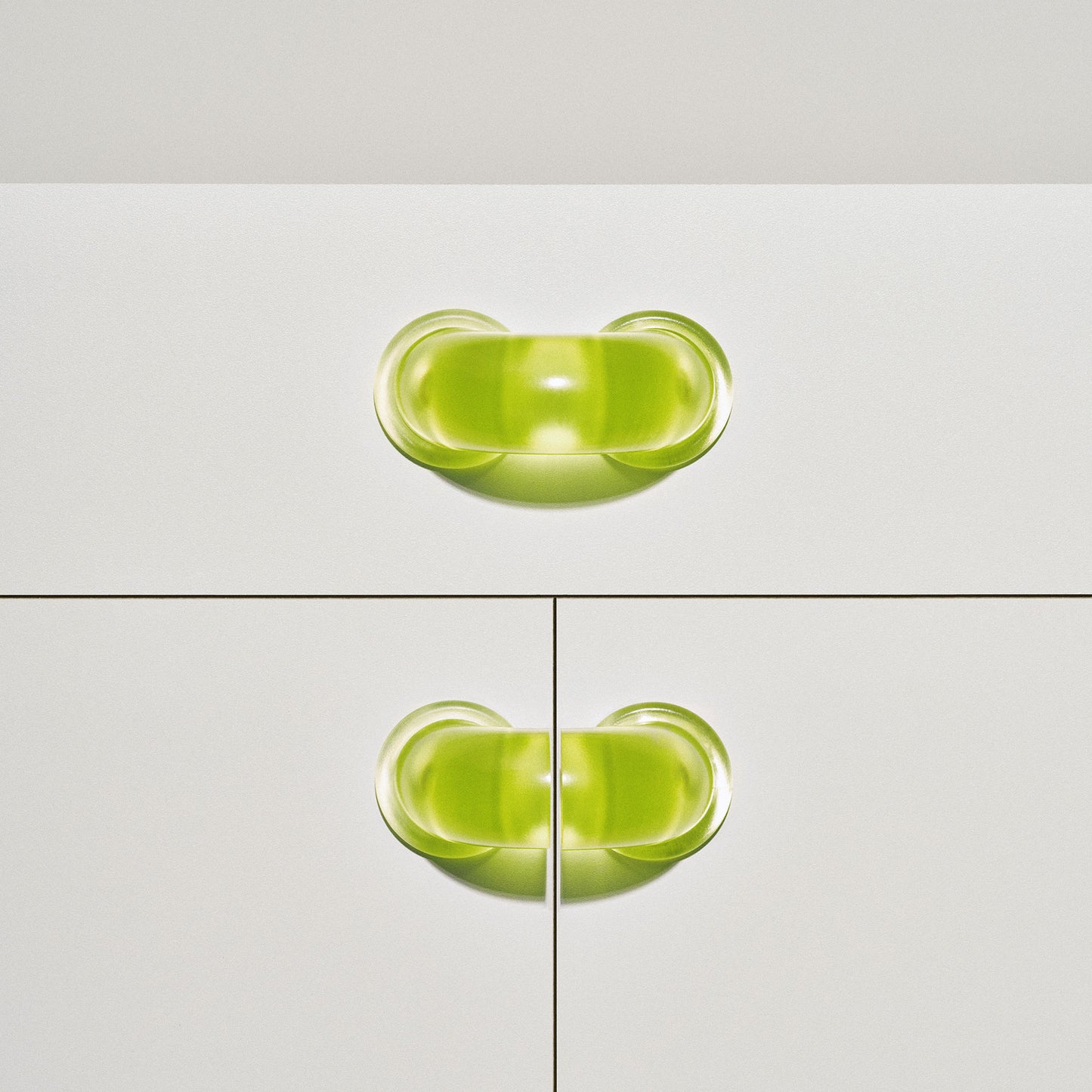 White cabinet with translucent yellow colored macaroni-shaped handles on a white background