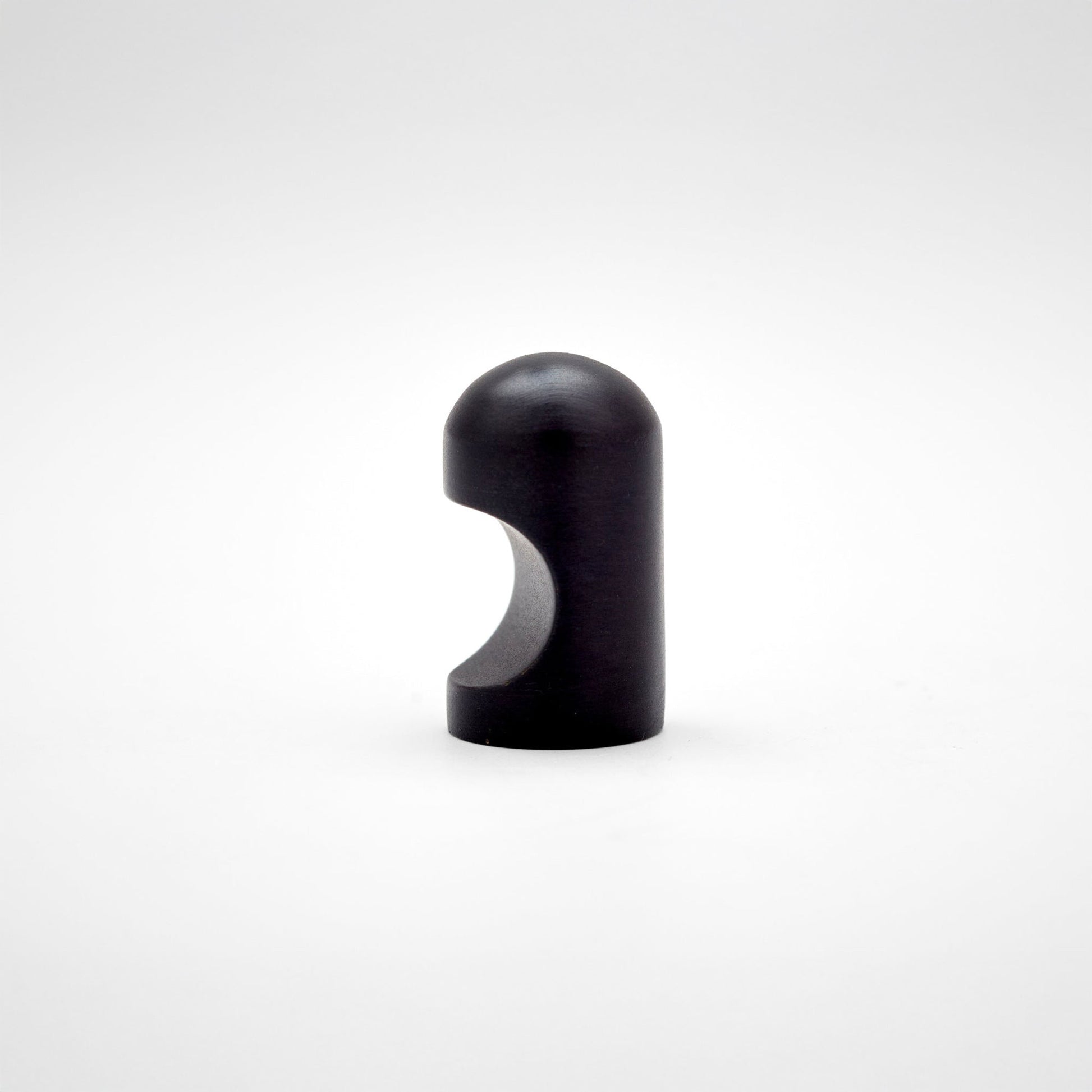 A small metallic cabinet knob with a rounded top and a curved cutout on the side, photographed on a clean light gray studio background.