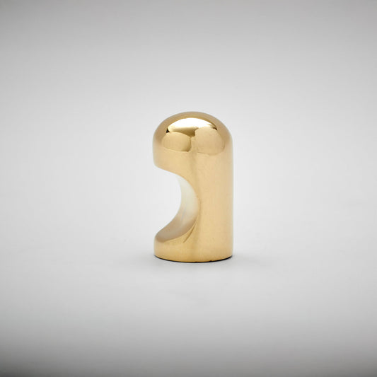 A small metallic cabinet knob with a rounded top and a curved cutout on the side, photographed on a clean light gray studio background.