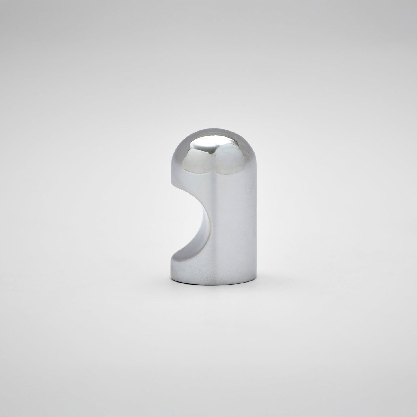 A small metallic cabinet knob with a rounded top and a curved cutout on the side, photographed on a clean light gray studio background.