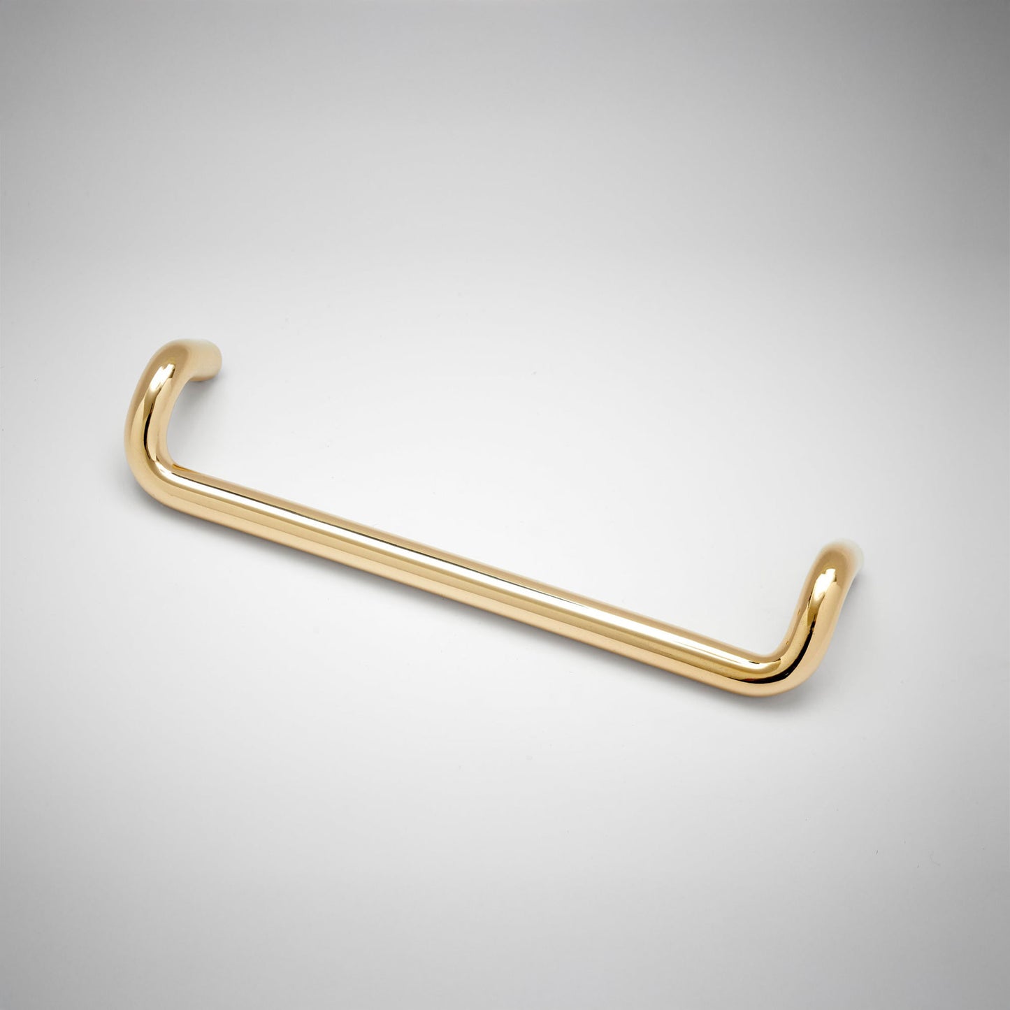A polished brass metal cabinet pull with a curved, U-shaped design, shown on a clean white background with a subtle vignette.