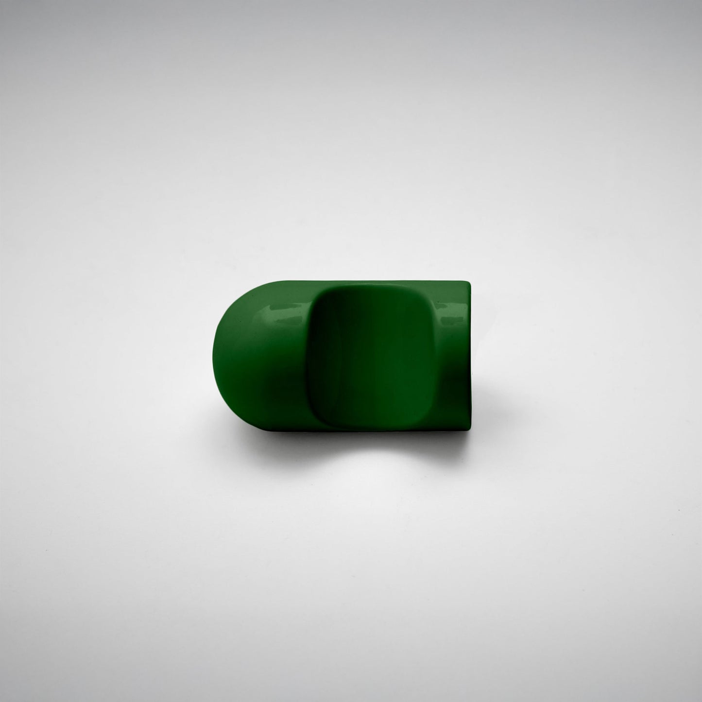 A glossy dark green cabinet pull with a rounded, modern dome-like shape, photographed on a neutral light gray background.