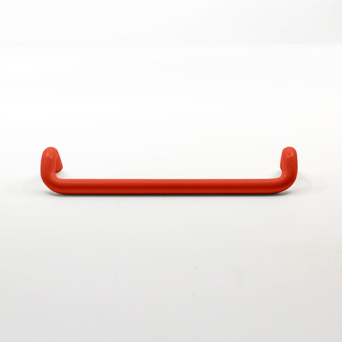 A single red metal cabinet pull handle with a curved bar and rounded ends, photographed on a clean white background.