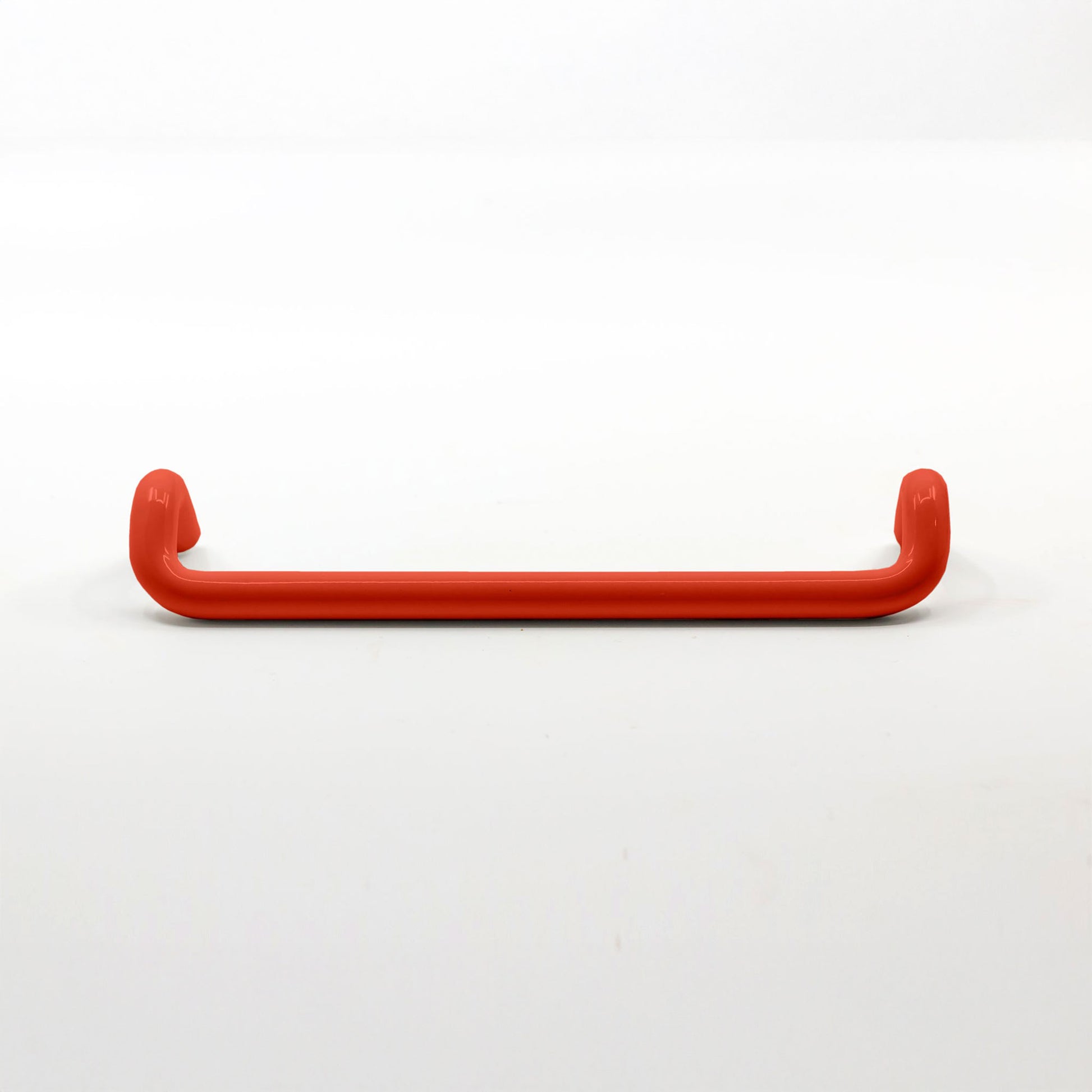 A single red metal cabinet pull handle with a curved bar and rounded ends, photographed on a clean white background.