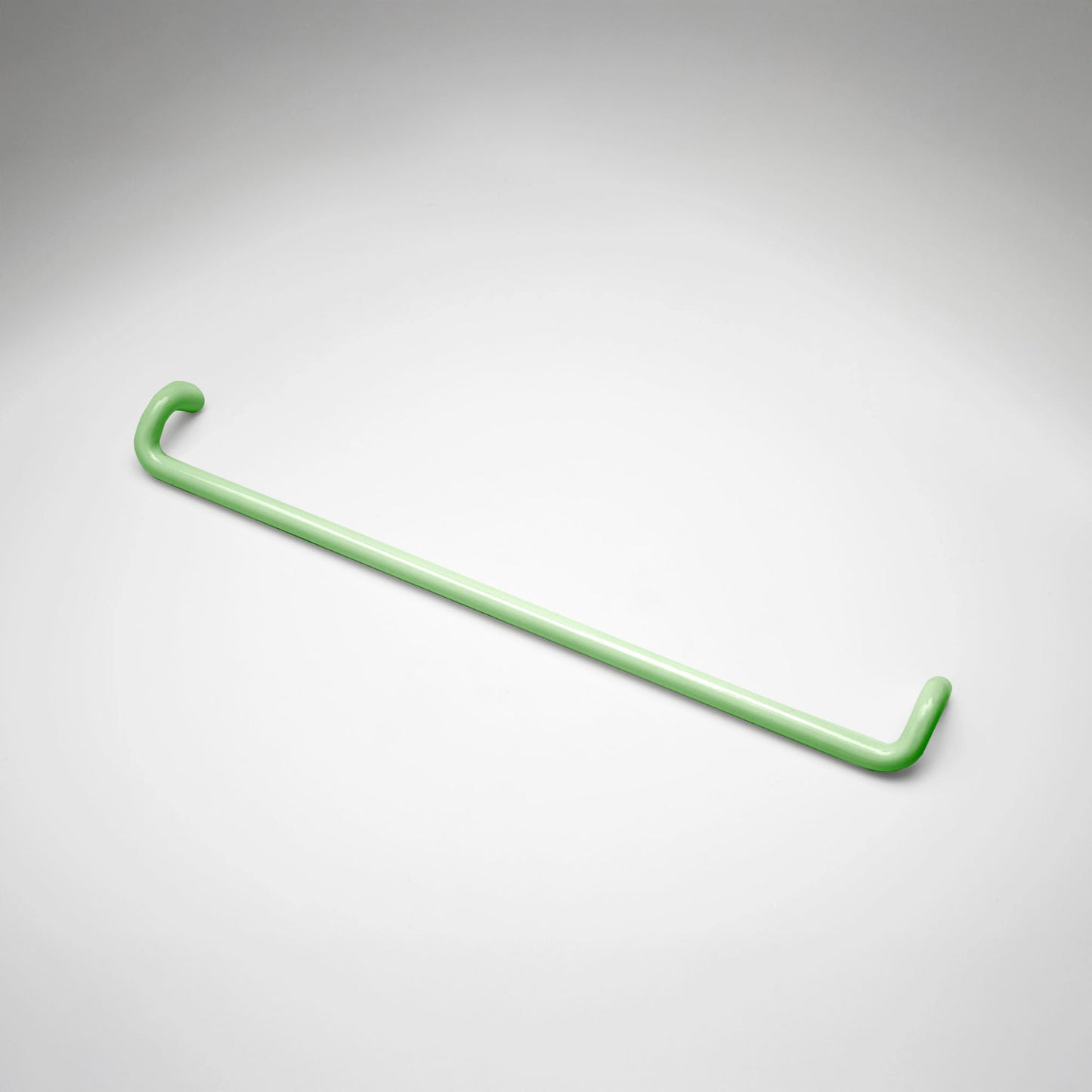 A minimalist mint green metal cabinet pull with a curved, modern design, shown on a clean light gray background.