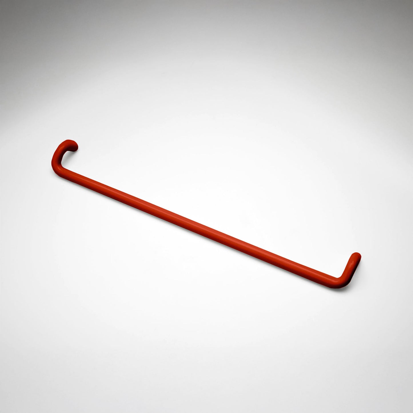 A minimalist red metal cabinet pull with a curved, modern design, shown on a clean light gray background.