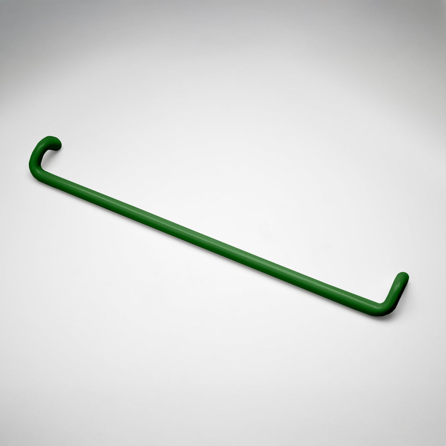 A minimalist green metal cabinet pull with a curved, modern design, shown on a clean light gray background.