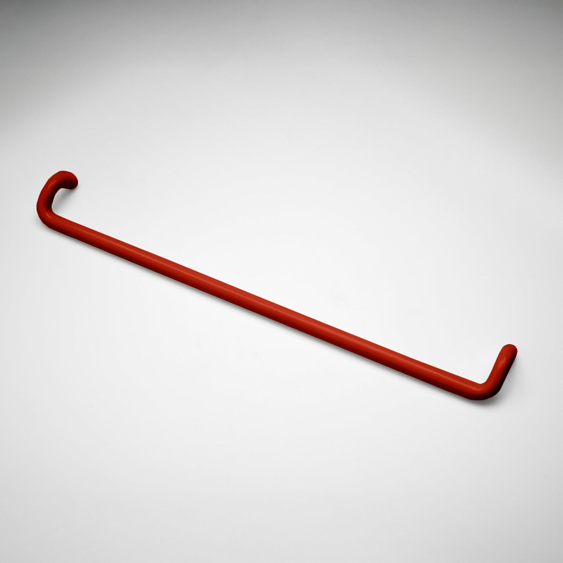 A minimalist red metal cabinet pull with a curved, modern design, shown on a clean light gray background.